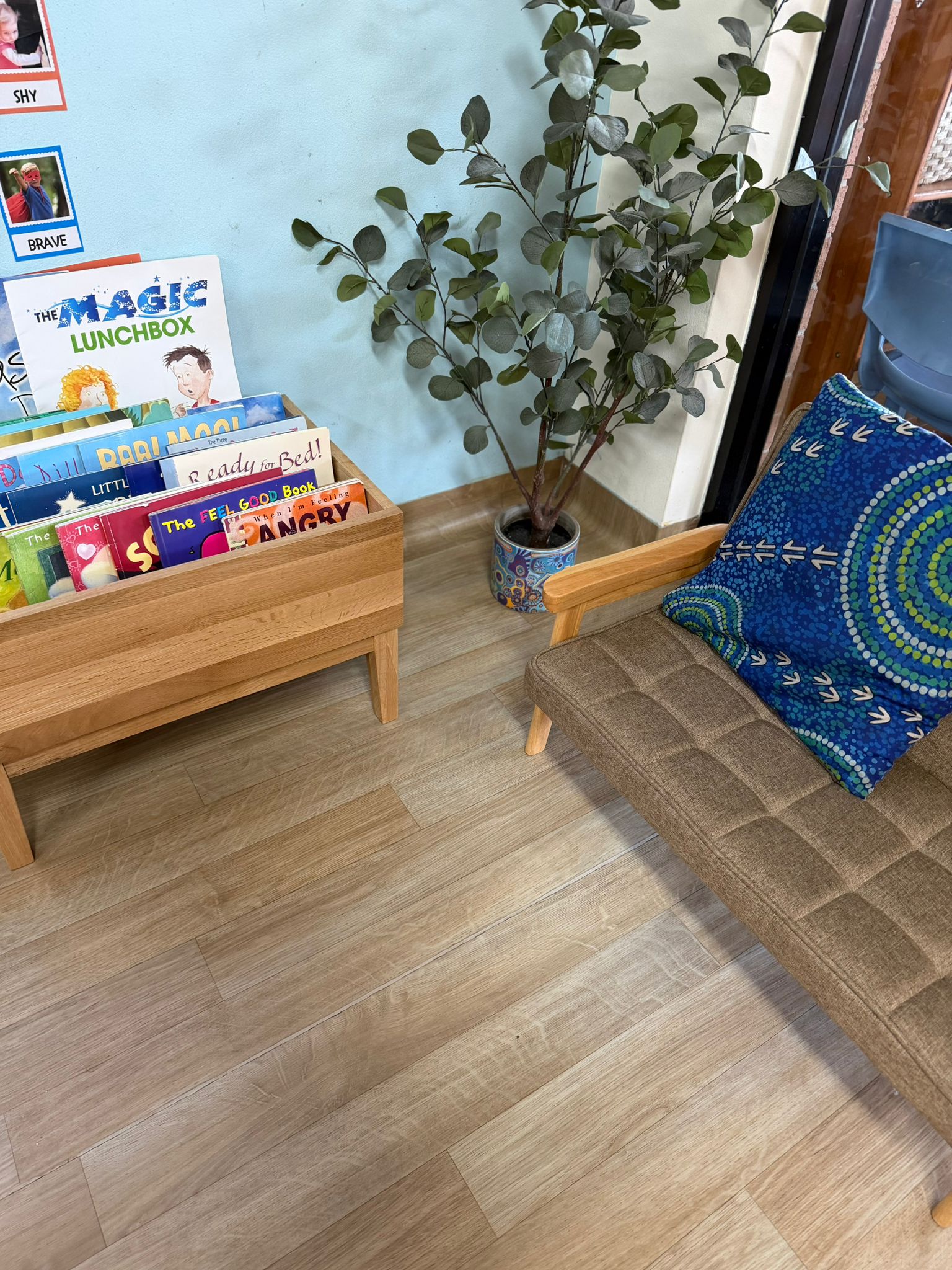 Cozy preschool reading library corner featuring a wooden bookshelf stocked with children's books and a comfortable armchair